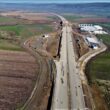 Cel mai mare tronson de pe teritoriul Sălajului al Autostrăzii Transilvania (A3) va fi materializat în șapte ani, în cel mai optimist scenariu.   Compania Națională de Administrare a Infrastructurii Rutiere (CNAIR) a prevăzut pentru tronsonul Poarta Sălajului – Zalău – Nușfalău o durată de execuție de 78 de luni. Ofertele pentru lotul Meseș sunt așteptate până la finalul acestei luni, după care ar urma proiectarea și, mai ales, execuția. Prețul s-a dublat. În trei ani “Licitația pentru lotul cu Tunelul Meseș a fost lansată acum mai bine de doi ani, pe 18 noiembrie 2020, pentru o valoare (inițială) de 4,4 miliarde lei. Este unul dintre cele mai importante și dificile proiecte ale CNAIR, cuprinzând cel mai lung tunel. Investiția bate pasul pe loc după mai multe ratări de licitații și de termene. Ultima dată, lotul Poarta Sălajului – Zalău – Nușfalău, cel mai mare contract pentru infrastructura rutieră, a fost scos la licitație la început de februarie, contractul pentru cei 41 km (Tunelul Meseș - 3 km) fiind cuprins între 7,5 și 8,8 miliarde de lei”, observă consilierul județean de sălăjean Nicolae Olar. “Ofertele pot fi depuse până la 26 aprilie. Să sperăm că, măcar acum autoritățile și-au făcut tema cum trebuie și în scurt timp vom avea un constructor desemnat. CNAIR a prevăzut pentru acest contract o durată de proiectare și execuție de 78 de luni, adică șase ani și jumătate. Ceea ce înseamnă că în cel mai optimist scenariu, dacă vom ști în câteva săptămâni constructorul, lotul Poarta Sălajului – Zalău – Nușfalău nu va fi gata mai repede anul 2031”, constată oficialul din Sălaj. Bode: porțiunea cu tunelul = 3 ani Directorul CNAIR, Cristian Pistol, a anunțat, în februarie, anularea licitațiilor inițiale, cu reluarea lor, la subsecțiunile 3B3 Poarta Sălajului – Zalău (inclusiv tunel rutier la profil de autostradă în zona Meseș) și 3B4 Zalău – Nușfalău “în special din cauza creșterii prețurilor pe piața de profil”. Fostul ministru al transporturilor, Lucian Bode, recunoștea că porțiunea cu Tunelul Meseș va fi greu de edificat. “Cei 3 km din tronsonul Poarta Sălajului – Zalău – Nușfalău, cu Tunelul Meseș, reprezintă o lucrare foarte grea, pentru care execuția va necesita trei ani”. Finanțarea pentru acest contract, cel mai mare ca valoare din istoria CNAIR, va fi asigurată prin Programul Operațional Transport. Președinții consiliilor județene din Regiunea Nord-Vest au trimis o scrisoare deschisă Guvernului României pentru a urgenta finalizarea A3. Ei solicită sprijin în vederea deblocării tuturor aspectelor legate de continuarea celei mai vechi și importante investiții din zonă, “proiect demarat în urmă cu mai bine de două decenii și marcat de o serie de disfuncționalități inadmisibile”. Lotul spre Bihor, pe mâna turcilor "Constructorul Nurol este în continuare în cărți pentru borna de 1.000 km de autostrăzi și drumuri expres în România. Am filmat cei 13 km dintre Nușfalău și Suplacu de Barcău. Contractul cu turcii a avut termen de finalizare în februarie 2023, fiind semnat în 30 septembrie 2020, pe 6 luni proiectare și 18 execuție. Ordinul de începere a fost emis în 1 februarie 2021 și proiectul tehnic a fost avizat în august 2021. Oficialii CNAIR nu au anunțat dacă au acordat antreprenorului extensii de timp. Ceea ce interesează, în ultimă instanță, pe toată lumea e când se va deschide: în iunie, termen fezabil, însă doar dacă se duc la bun sfârșit procedurile birocratice și execuția propriu-zisă a soluției provizorii de conectare cu Drumul Național 19B lângă Porț, la sud de Suplacu de Barcău", constată Asociația Pro Infrastructură Proiectul Autostrăzii Transilvania (Braşov – Borş), parte din A3, a început în 2004, în baza unui contract încheiat cu compania americană Bechtel, ce trebuia executat până în 2012. A3 a fost împărțită inițial de autoritățile române în două proiecte, București – Brașov și Brașov – Cluj-Napoca – Borș, lungimea sa fiind de 584 km.